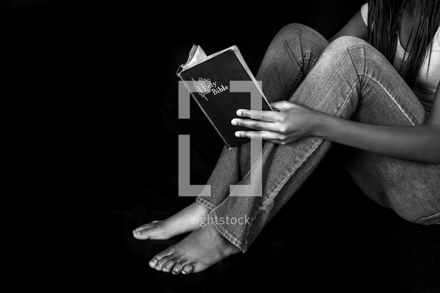 Teen girl sitting reading a Bible 