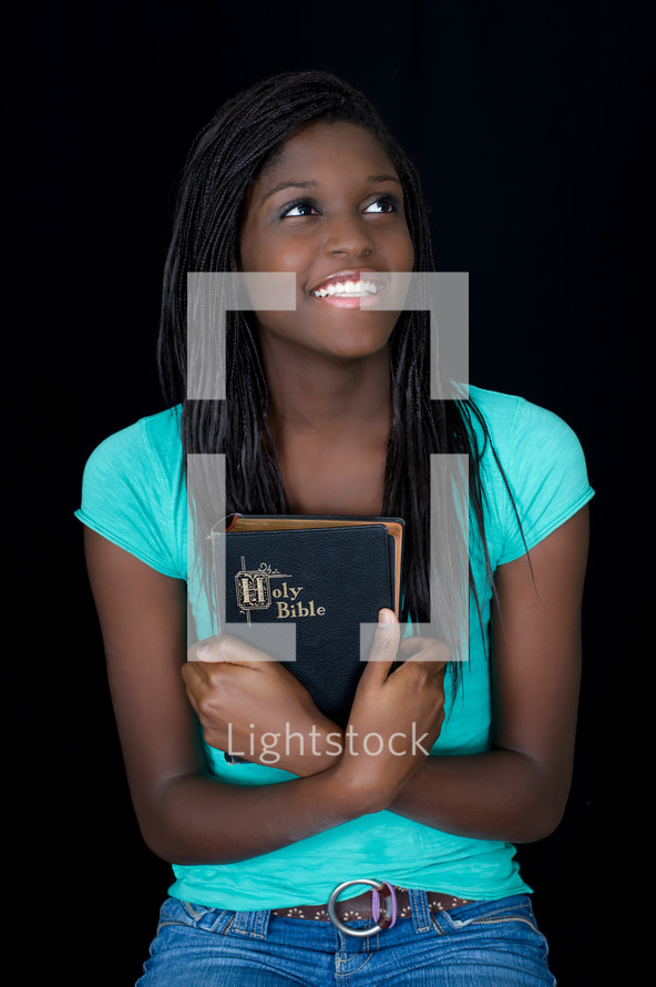 A teen girl holding a Bible close to her heart