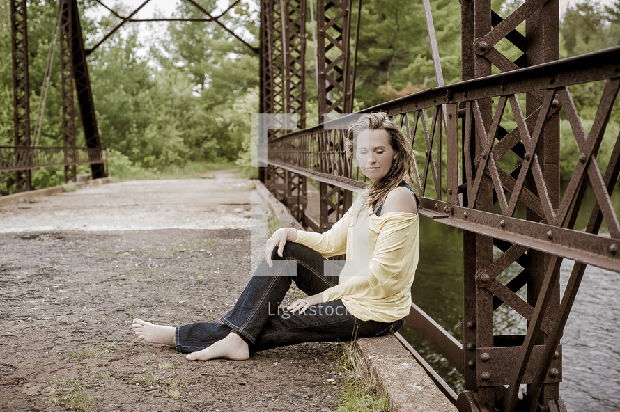 woman sitting on a bridge 