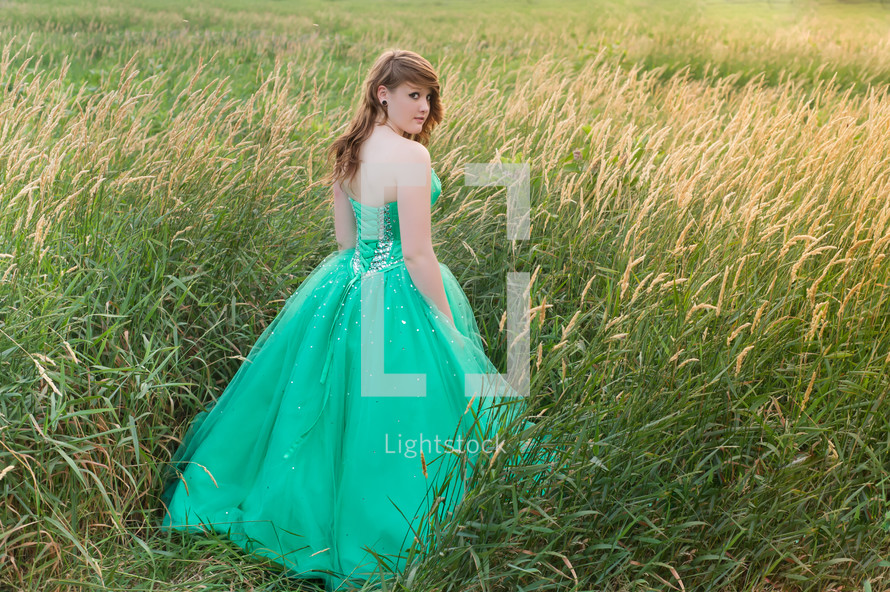 teen in a green prom dress in a field 