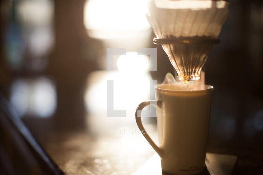slow brew coffee filter and coffee mug in morning sunlight 