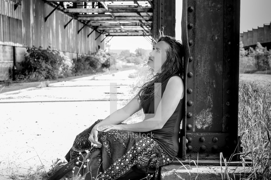 woman sitting under a bridge 