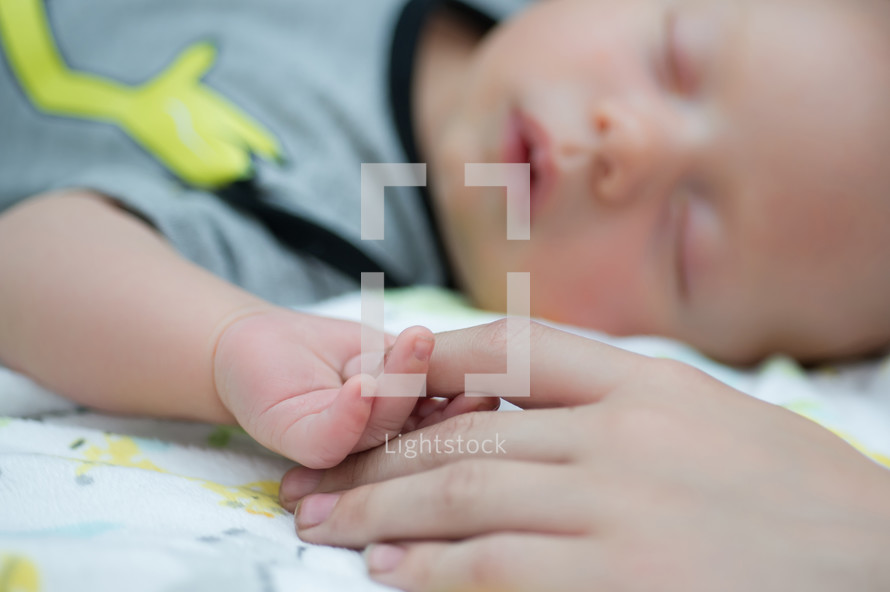 infant son holding mom's finger 