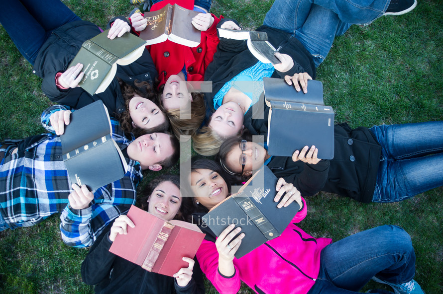 youth group lying in the grass reading Bibles 