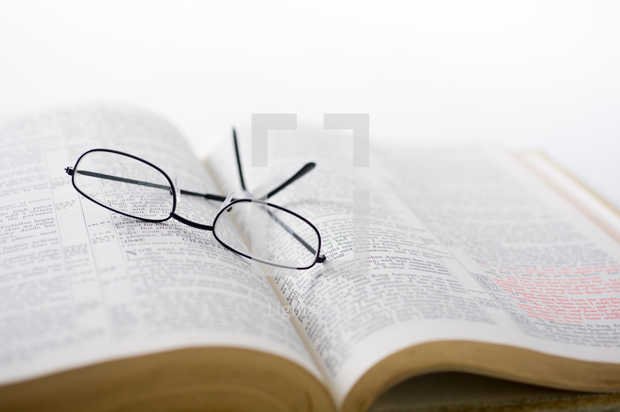 Glasses on the pages of an open Bible.