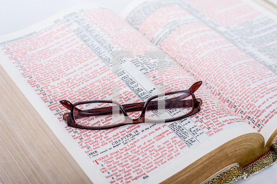 Glasses on the pages of a Bible open to the Book of John.