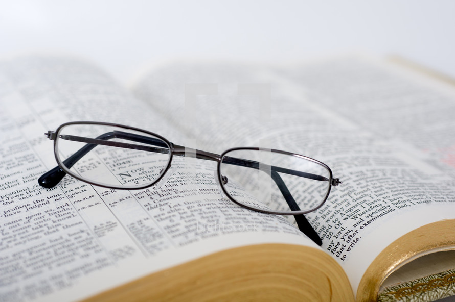 Eye glasses on the pages of an open Bible.