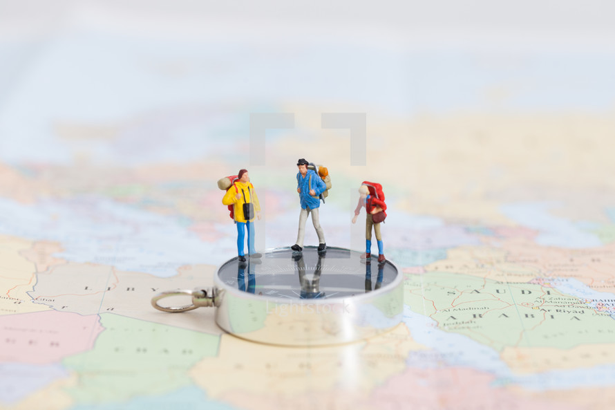miniature figurines on a compass on a map 