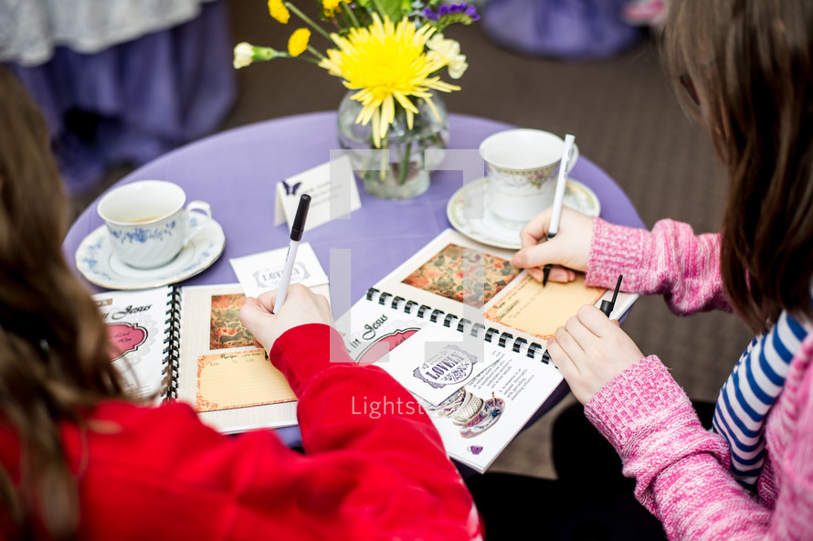 girl writing in journals at a tea party