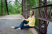 woman sitting on a rustic bridge