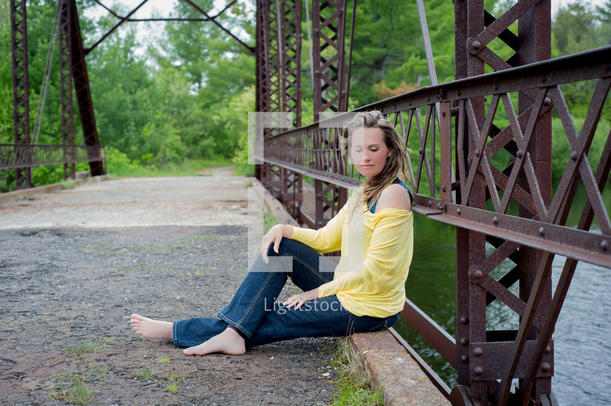 woman sitting on a rustic bridge
