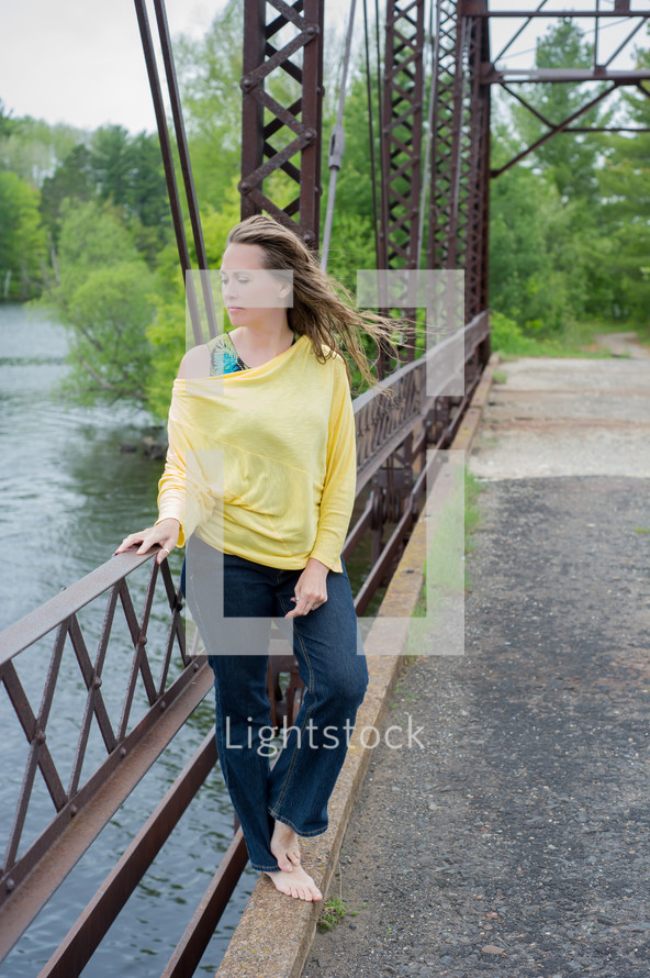 woman looking out at the water standing on a bridge 