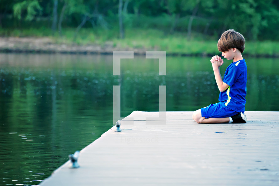 boy child kneeling on a dock 