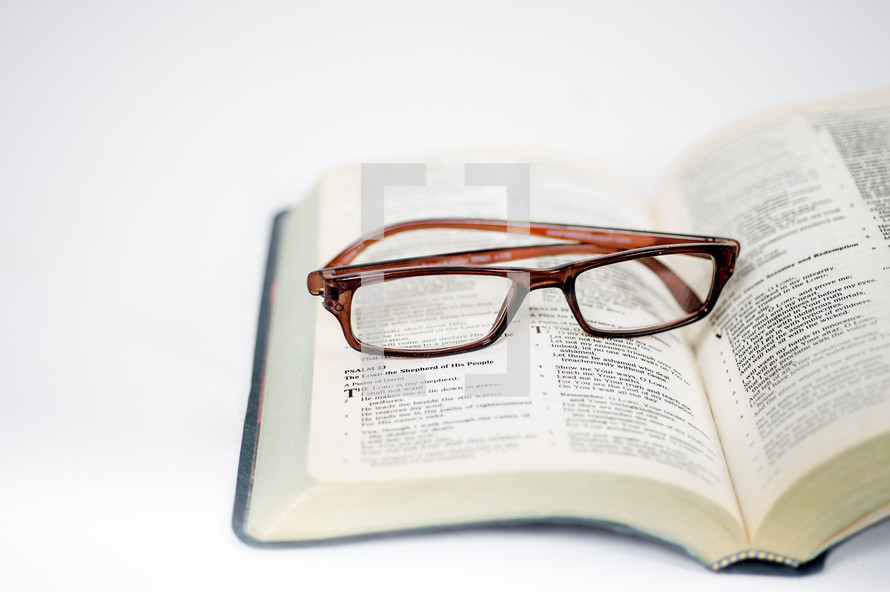 An open bible with a pair of glasses laying on it