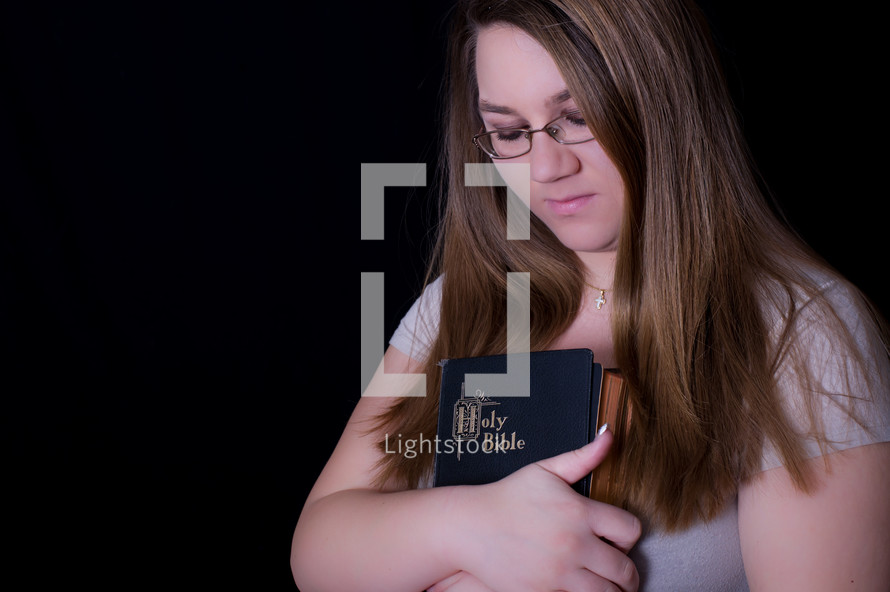 A teen girl holding a Bible close to her heart