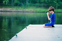 boy child kneeling on a dock 