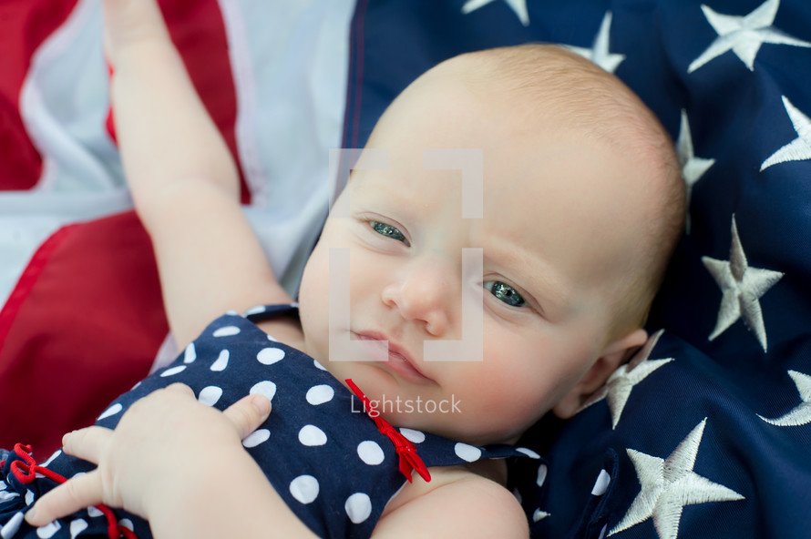 infant girl sleeping on an American flag 