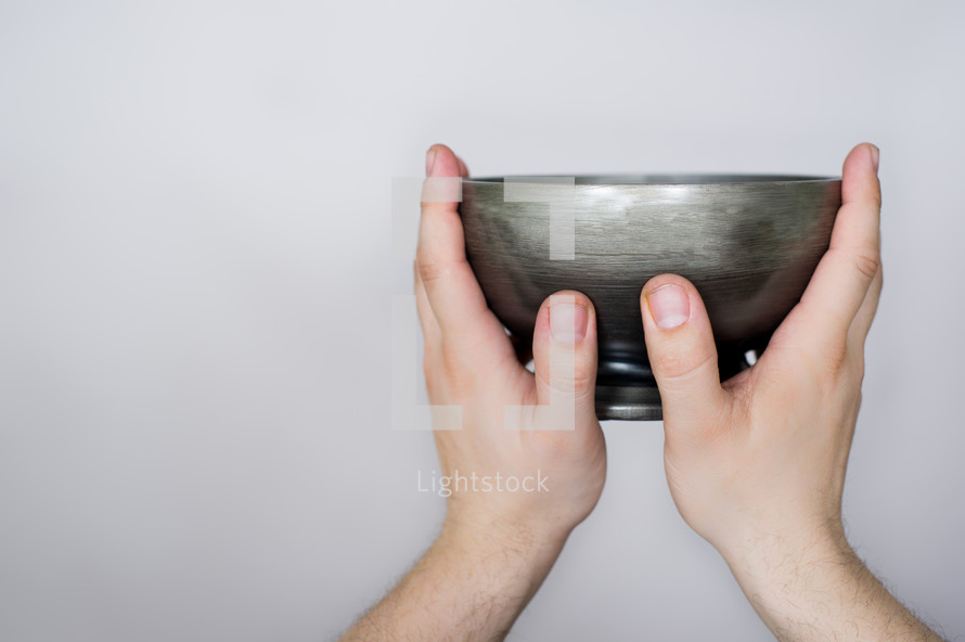 Hands holding up pewter bowl.