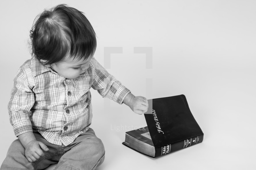 toddler boy opening a Bible 