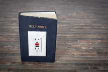 Electrical outlet on the Holy Bible.