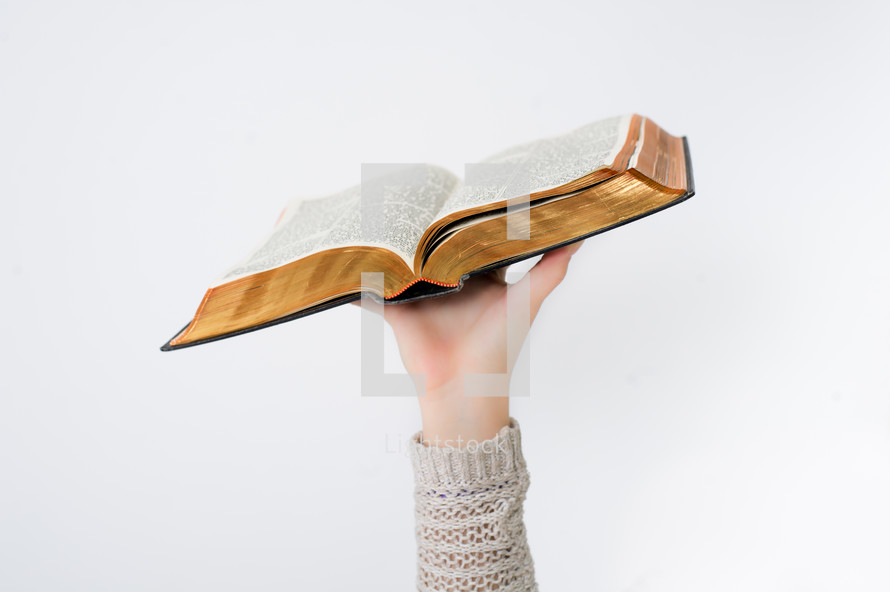 Hand lifting an open Bible.
