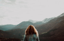 a woman looking out at the view of mountains 