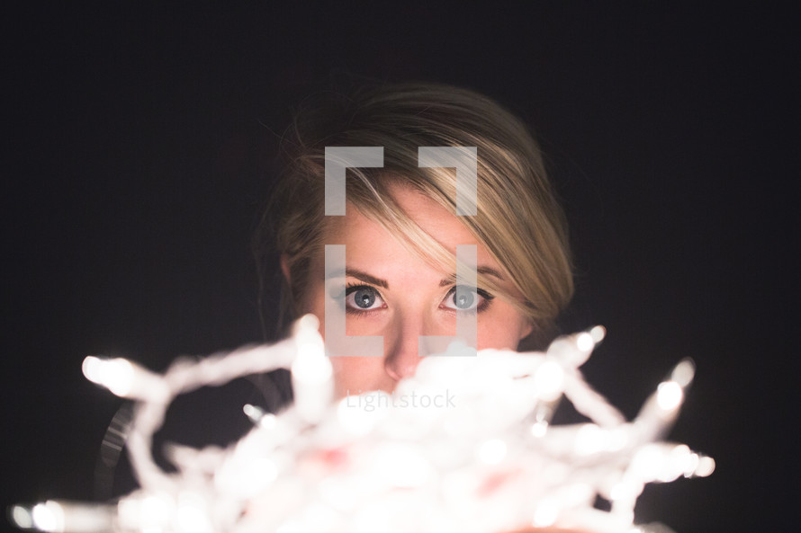 face, eyes, woman, holding, string of lights, Christmas lights, light 