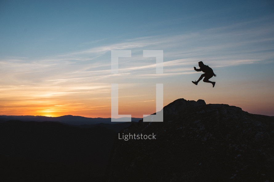 silhouette of a leaping man at sunset on a mountaintop 