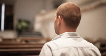 Man sitting in a church pew.