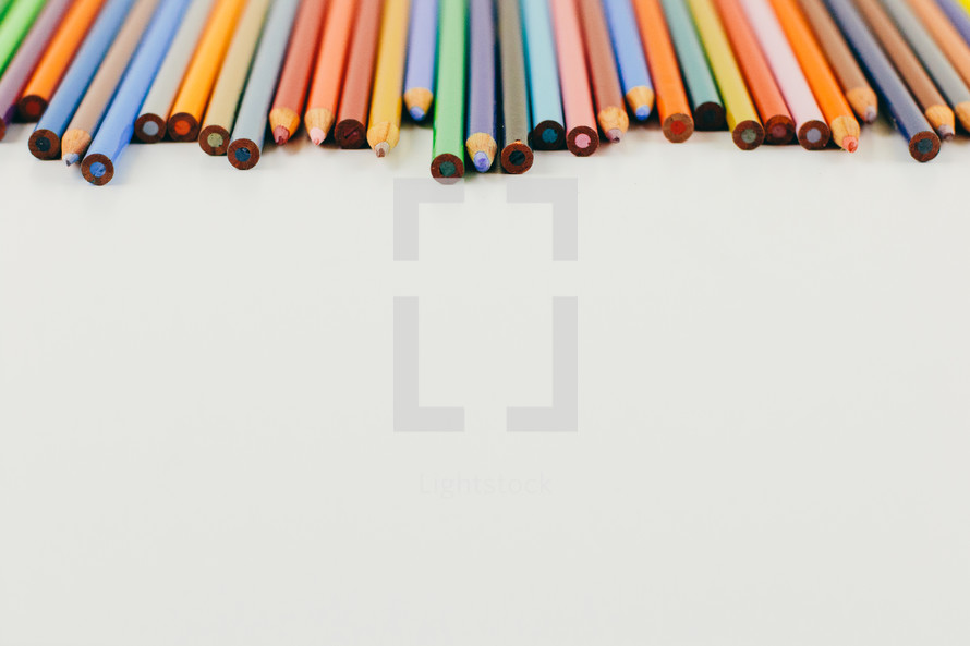 row of colored pencils on a white background 