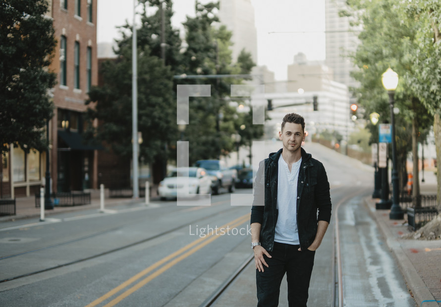 portrait of a man standing on the side of a downtown street 