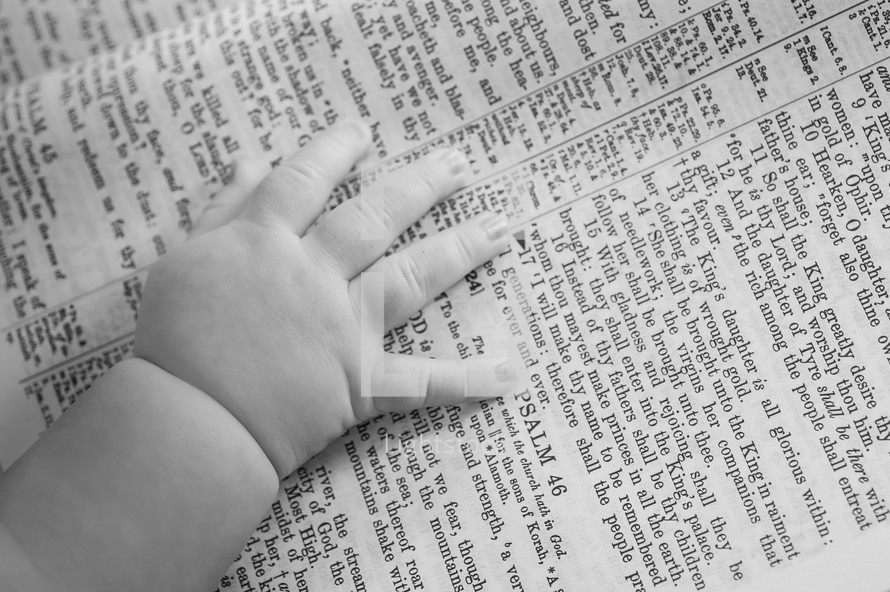 Infant hands laying on a bible