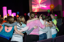 Girls in a church service with arms around each other.