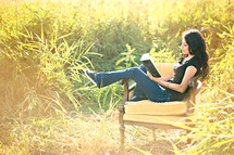 woman reading the Santa Biblica in a chair outdoors 