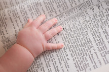 Close-up of infants hand laying on a bible opened to Psalm 46