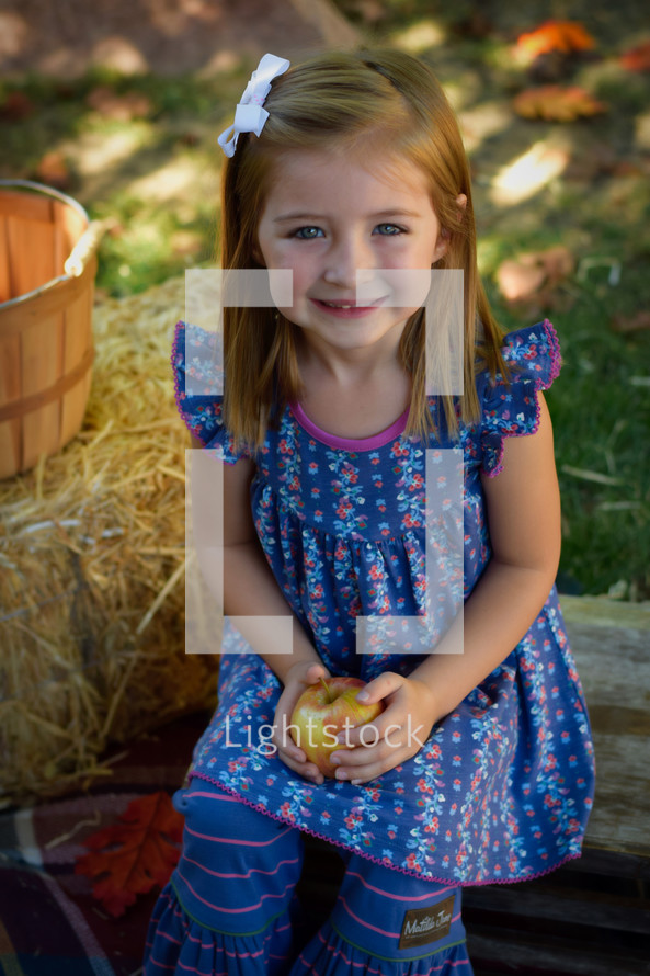 smiling toddler girl holding an apple 