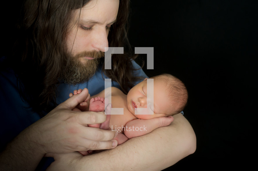 father with long hair holding his newborn baby 