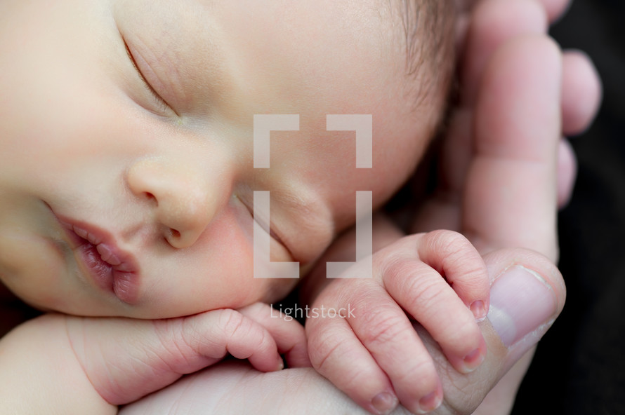 Adult hands holding a newborn infant.