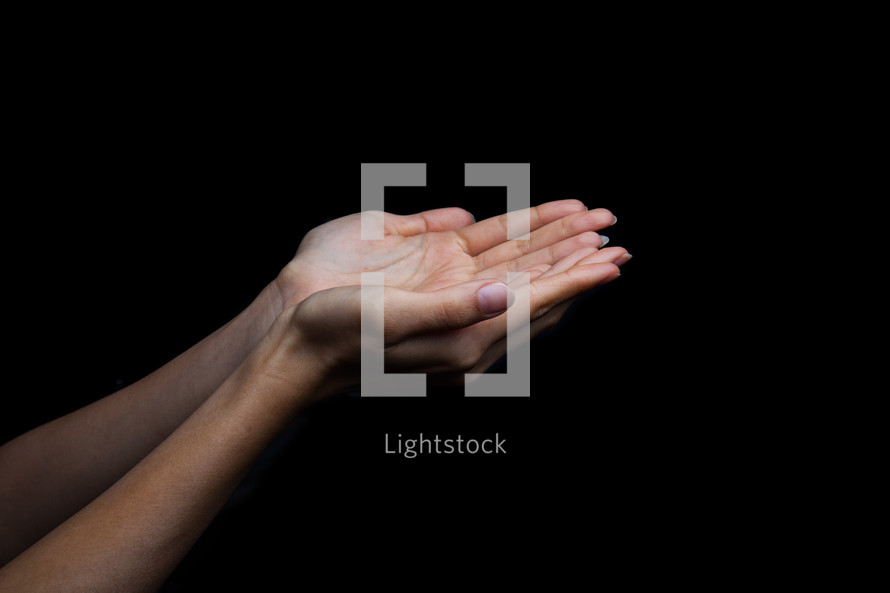 cupped hands against a black background 