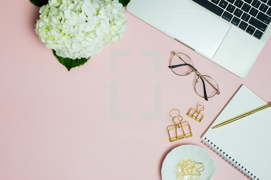 pink computer desk with notebook and hydrangeas 