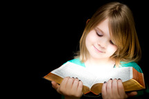 A girl child reading a Bible 
