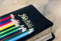 row of colored pencils on a Bible 