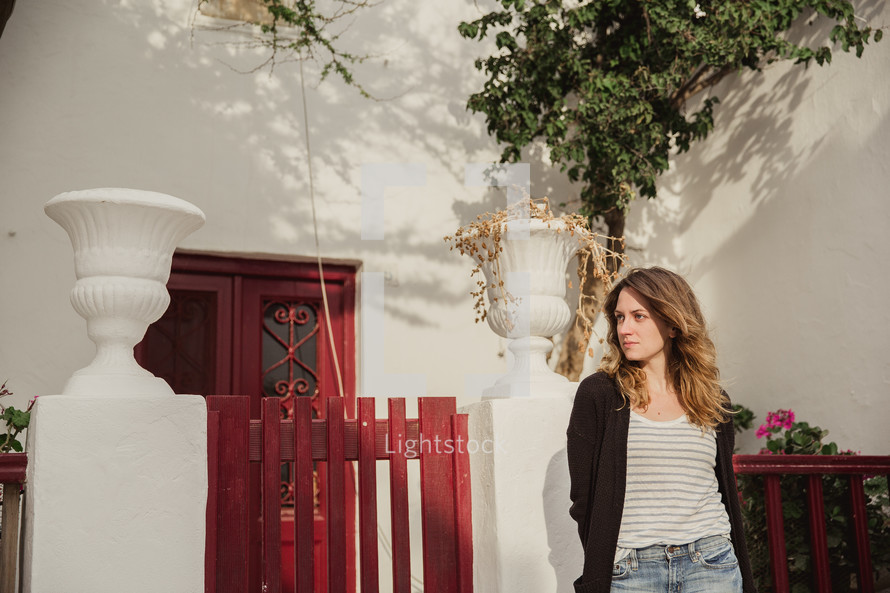 woman standing outdoors near a red fence in Greece 