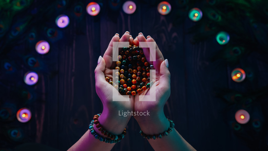 Woman holding wooden beads with candles surrounding her