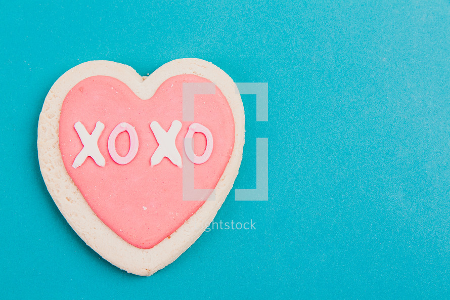 A pink and white Valentine candy heart on an aqua background.