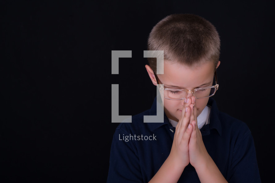 A boy child with glasses praying 