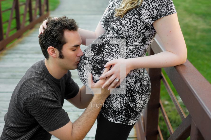 man kissing a pregnant belly