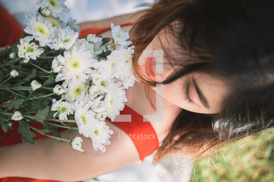 a woman in a red dress holding a bouquet of daisies 