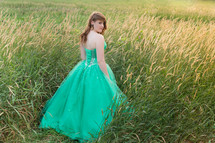 teen in a green prom dress in a field 