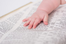 Baby's hand laying on an open bible